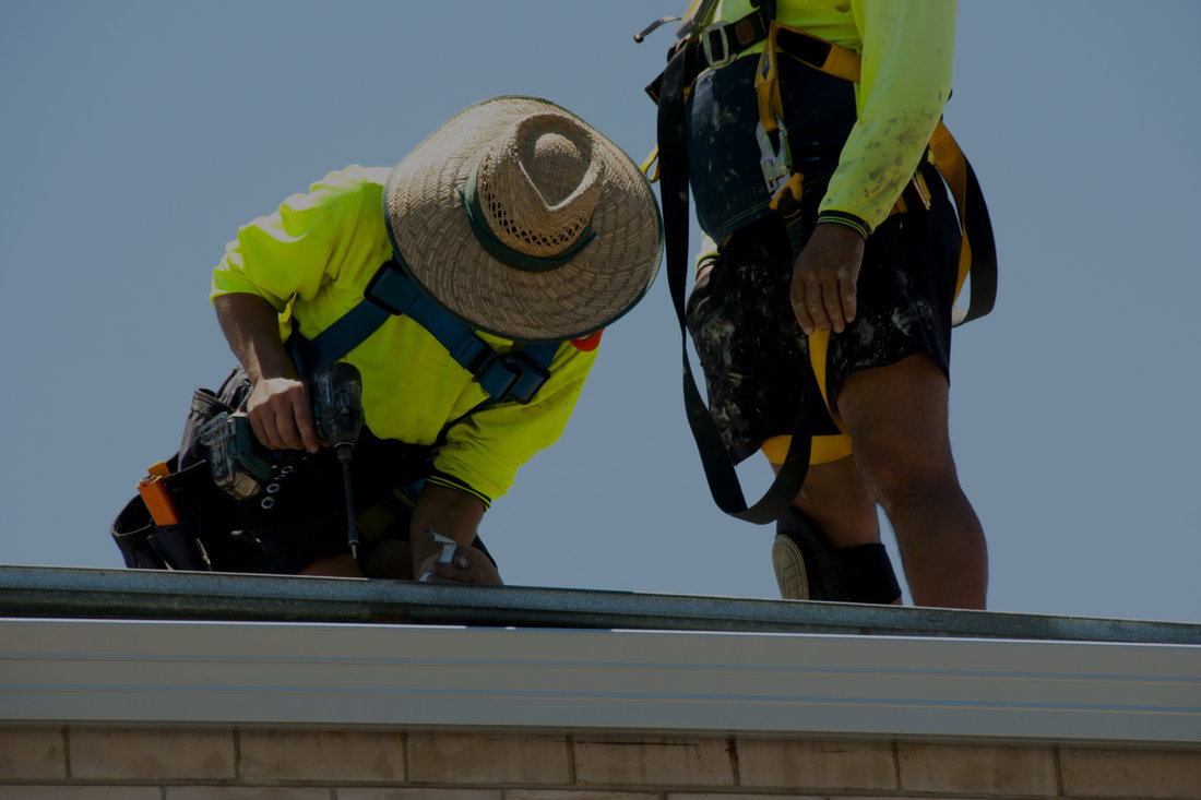 Roofers working on a metal roofing detail